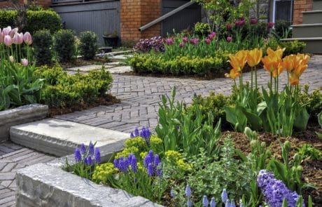 hardscaped brick paver patio with bright flowerbed surrounded by mulch