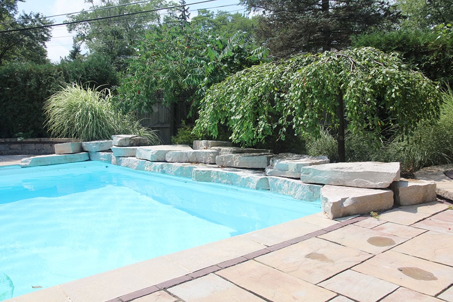 custom built pool with rock landscaping and paver stone patio