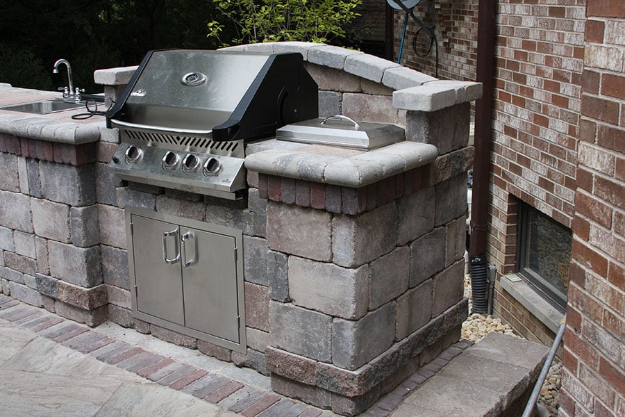 brick outdoor kitchen with grill and sink on paver stone patio. hardscaping done by bret-mar