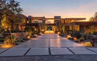 a modern, elegantly designed entryway showcases a stunning illuminated driveway, featuring sleek path lights and artistic landscaping that enhances the ambiance of the evening setting.