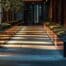 a sleek, modern urban pathway is framed by gleaming metal landscape edging, casting striking shadows under soft artificial lighting, highlighting its contemporary design.