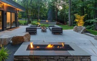 a contemporary outdoor living space showcases sleek hardscaping elements like stylish stone pathways, elegant patio seating, and a modern fire pit, all expertly arranged to create a striking and inviting backyard retreat.